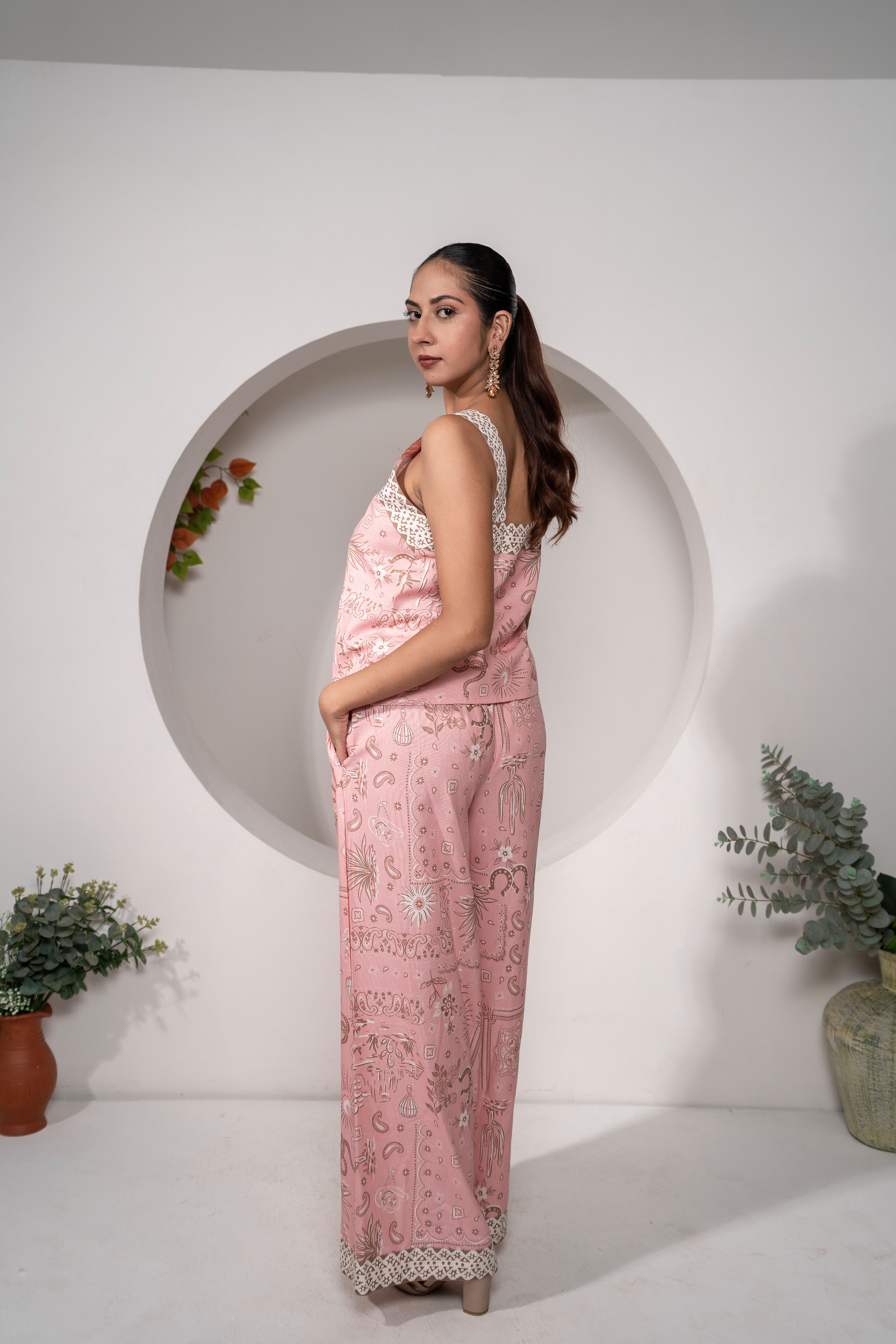 Woman wearing Desert Rose Pink Printed Cotton Co-ord Set – Vacation & Resort Wear outfit standing in front of a white wall with decorative elements.