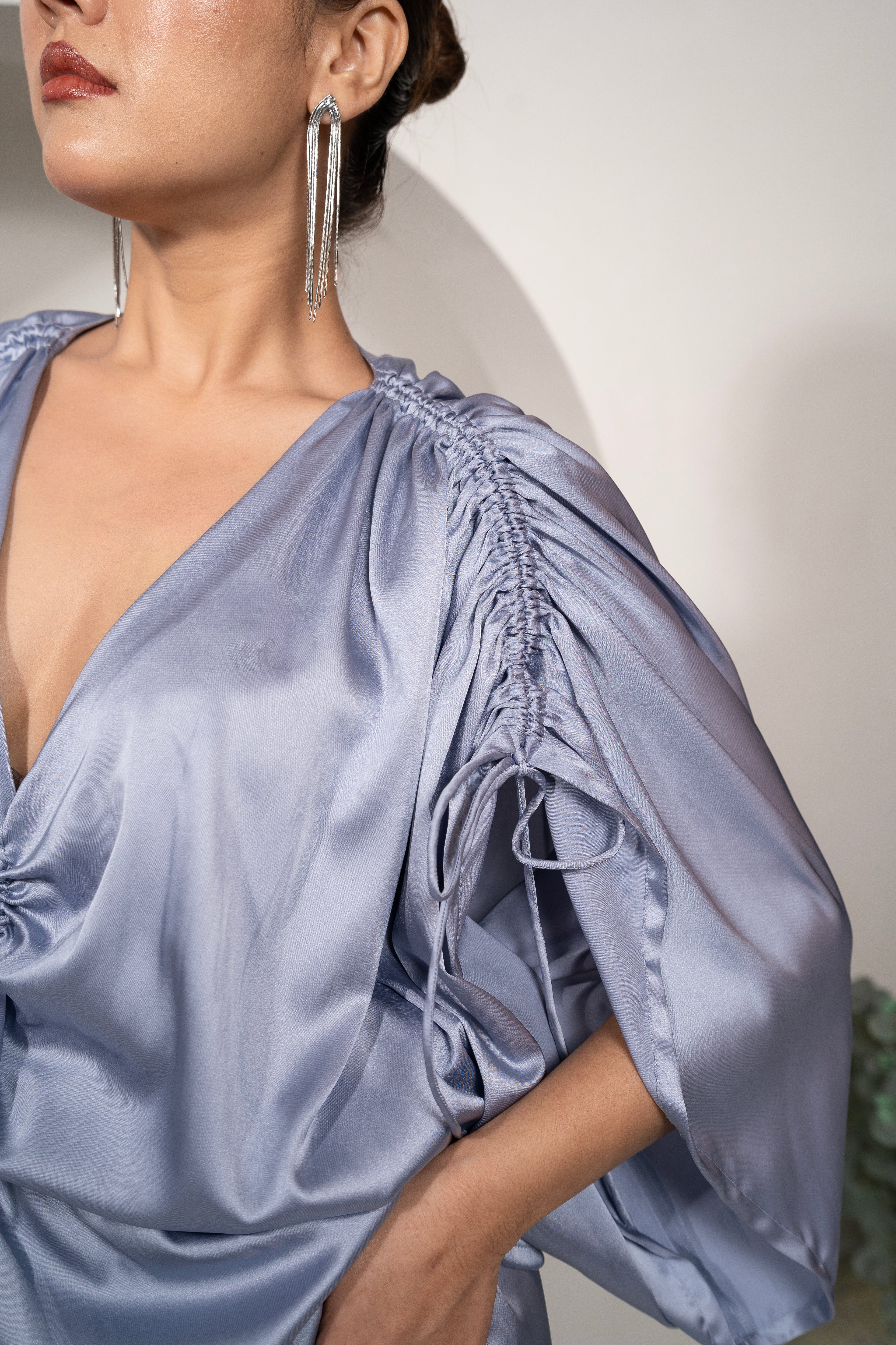 Woman wearing a Khamna Azure Whisper Ruched Tie-Top – Satin Drawstring Peplum zoom in against a neutral background