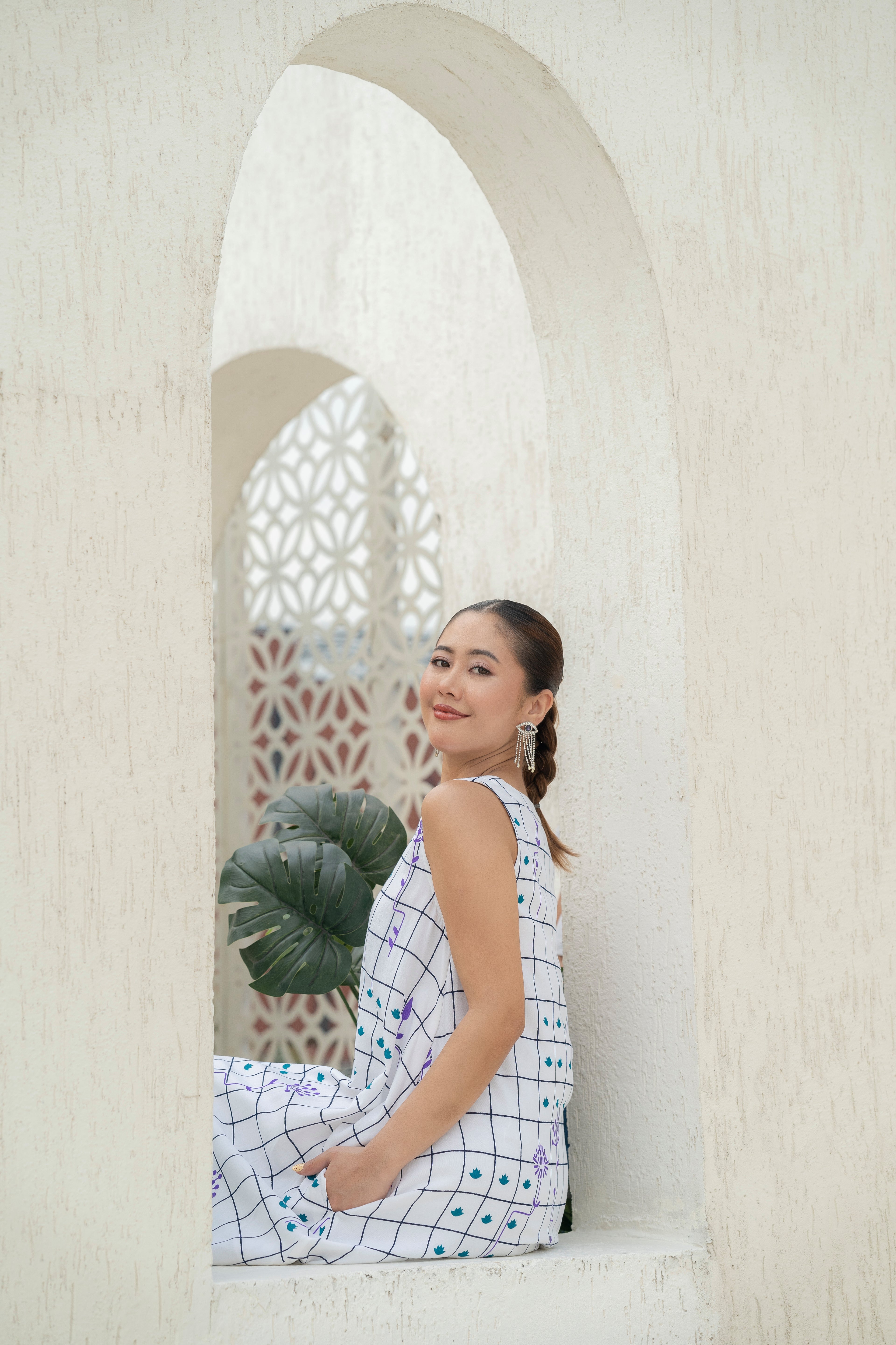 Woman sitting in a decorative archway with a plant
