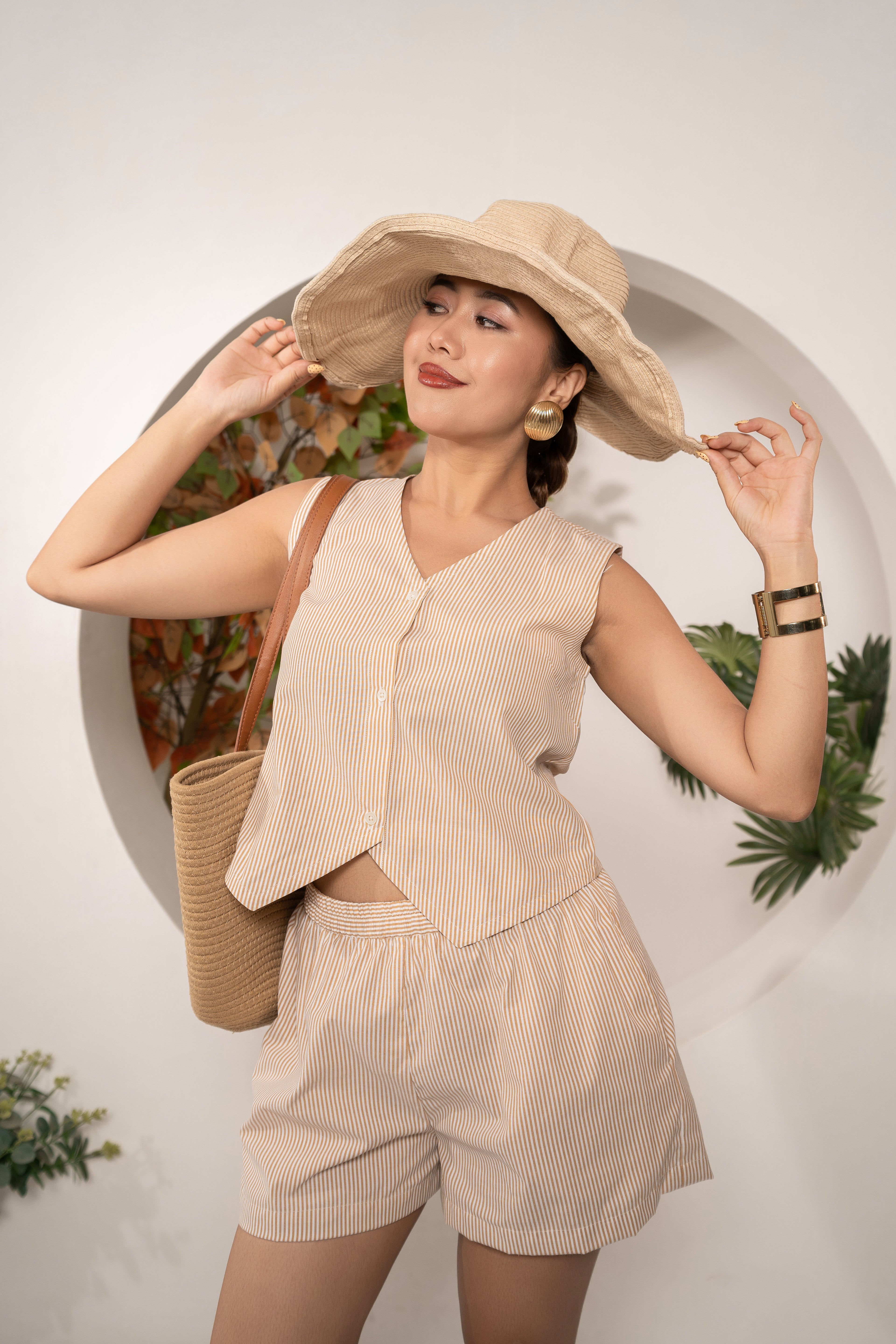 Woman in a Sandstone Stripe Vest – Cotton Y/D Sleeveless Top with a wide-brimmed hat against a white background