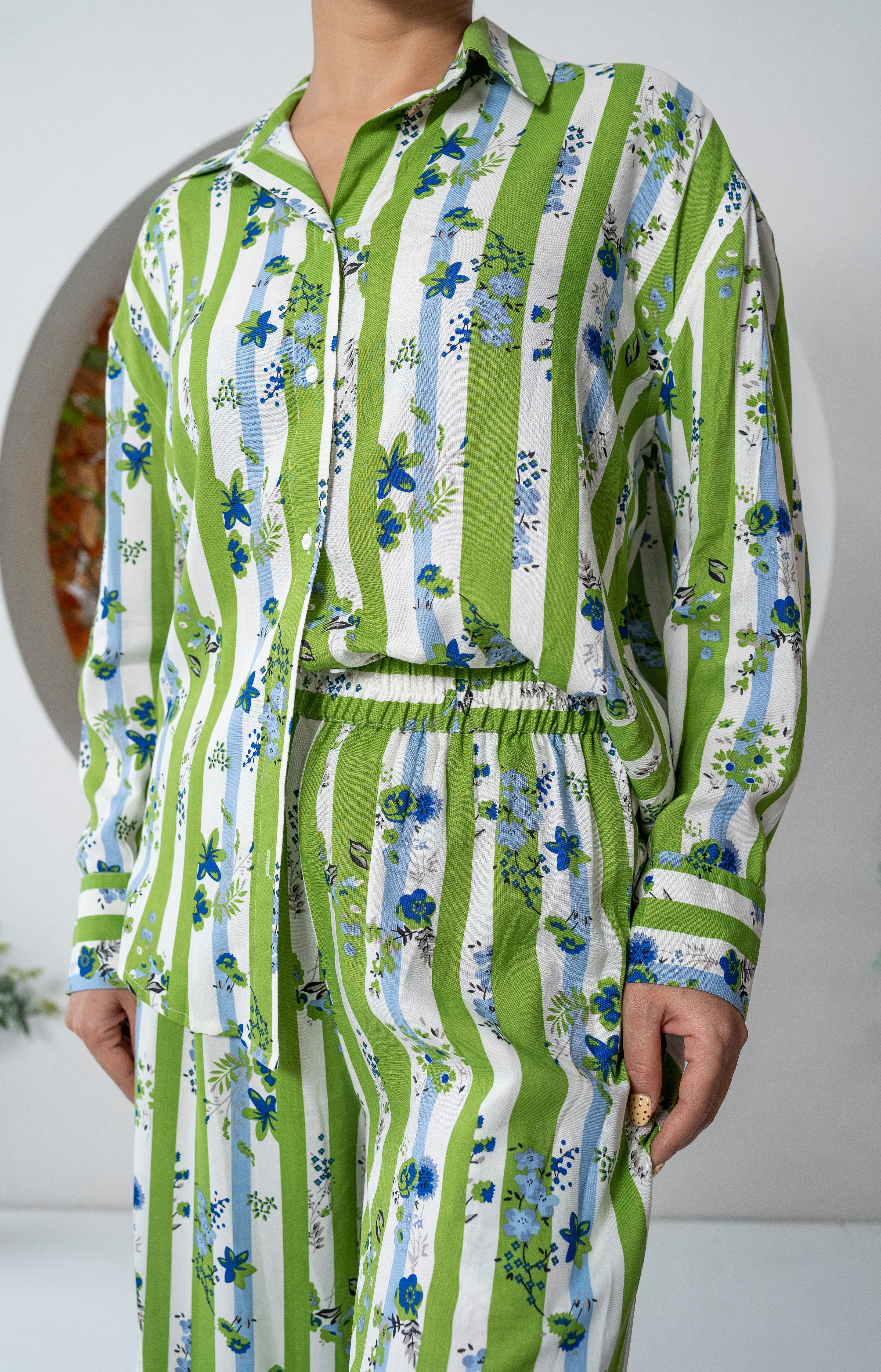Green and white striped Khamna Verdant Bloom – Oversized Shirt with floral patterns worn by a person.