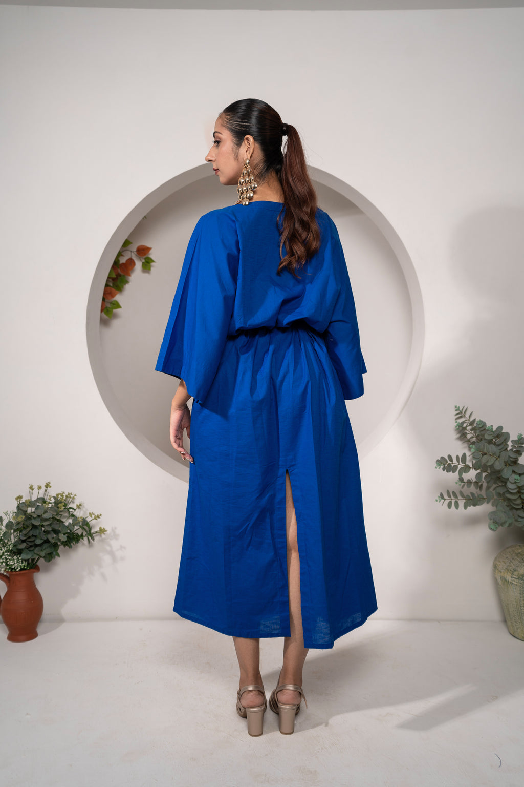 Woman wearing Khamna's Ocean Mirage Kaftan Dress – Cotton Linen Tieable Drape with a slit, Perfect for your holidays standing in front of a white wall.