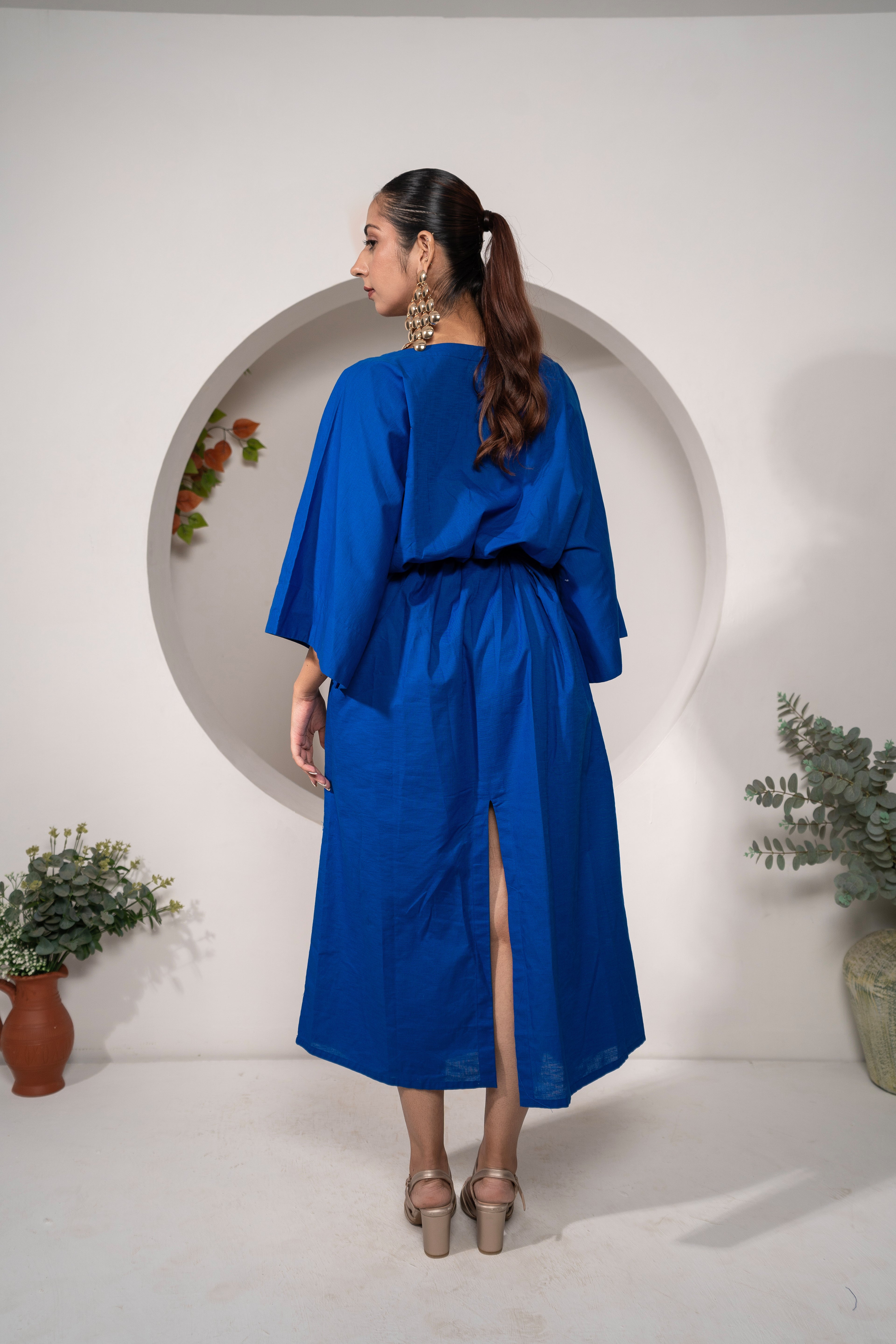Woman wearing Khamna's Ocean Mirage Kaftan Dress – Cotton Linen Tieable Drape with a slit, Perfect for your holidays standing in front of a white wall.