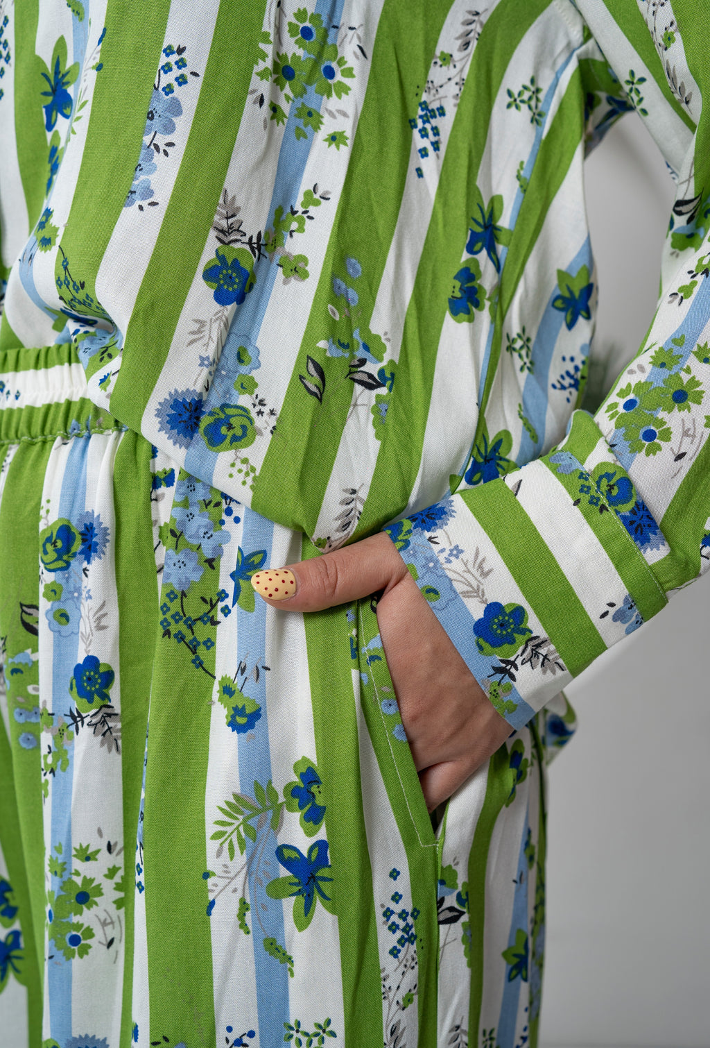Close-up of a green and white striped garment with floral patterns on a plain background