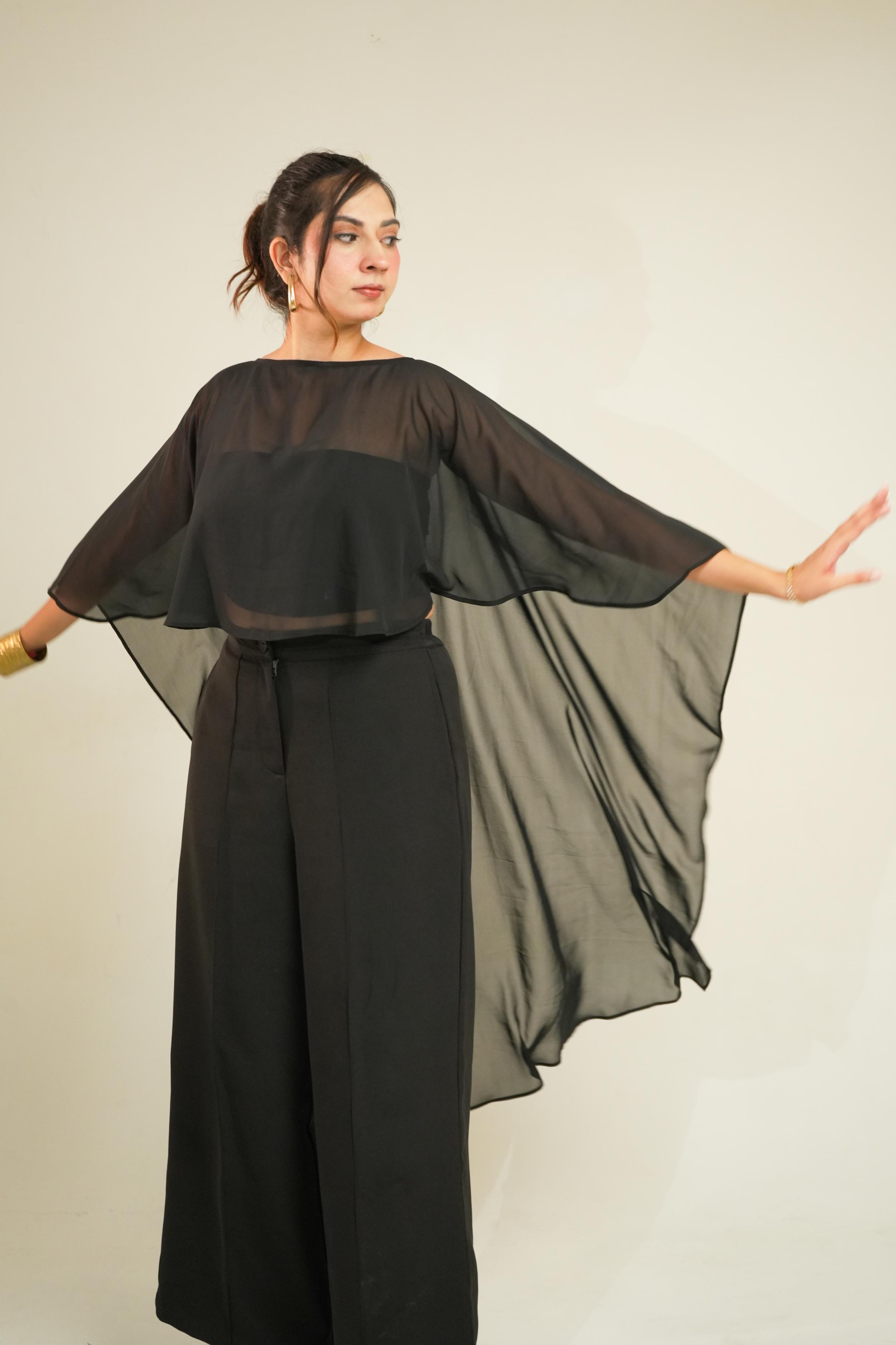 A woman modeling Vrinda Three-Piece Black Co-ord Set | Tube Top, Cape & Wide-Leg Pants posed against a plain light beige studio background.
