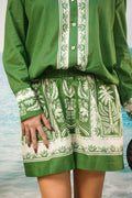 A person wearing a green and Yoshita Green Cotton Co-ord Set | Oversized Shirt & Shorts photographed against a blurred beach or water background.